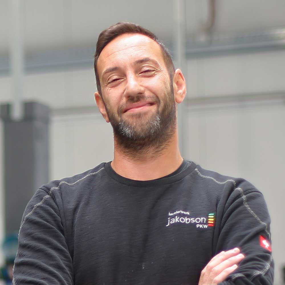 Über Uns-Mehmet Über Uns-Portrait des Mitarbeiters Mehmet mit nach vorn verschränkten Armen