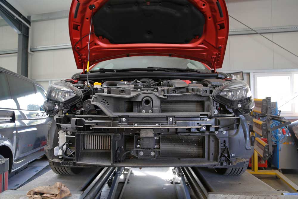 Unfallinstandsetzung-Geöffnete Motorhaube eines roten PKWs