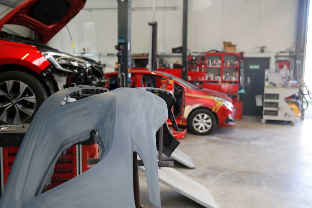 Unfallinstandsetzung-Graues Autoteil-im Hintergrund ist die Werkstadt von Lackierwerk Jakobson PKW zu sehen