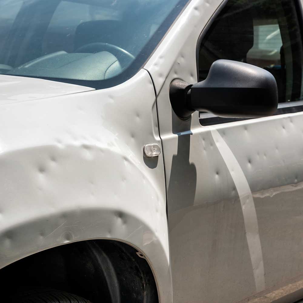 jakobson-dienstleistungen-hagelschadenbeseitigung Dienstleistungen-Hagelschadenbeseitigung-Nahaufnahme eines hellen Autos mit vielen Dellen