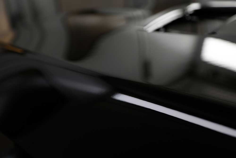 Hagelschadenbeseitigung-Nahaufnahme eines schwarz glänzenden Lackes eines schwarzen Autos