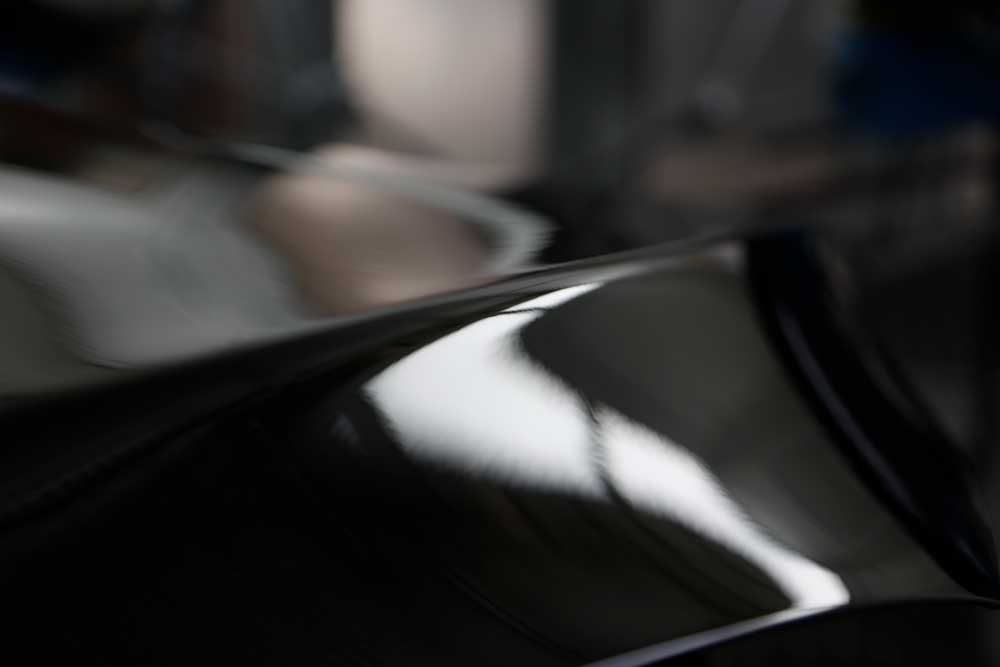 Hagelschadenbeseitigung-Nahaufnahme eines schwarzen Lackes von einem schwarzen Auto, an dem zuvor ein Hagelschaden war