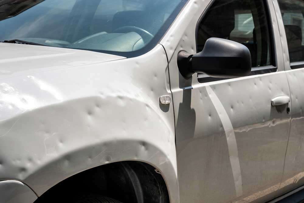Hagelschadenbeseitigung-Nahaufnahme eines hellen Autos mit vielen Dellen