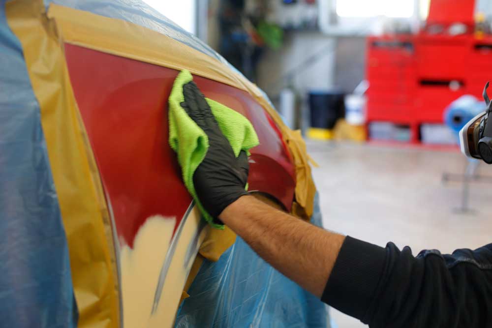 Aufbereitung von Leasingrückläufern-Mitarbeiter reinigt den abgeklebten Bereich mit einem grünen Tuch