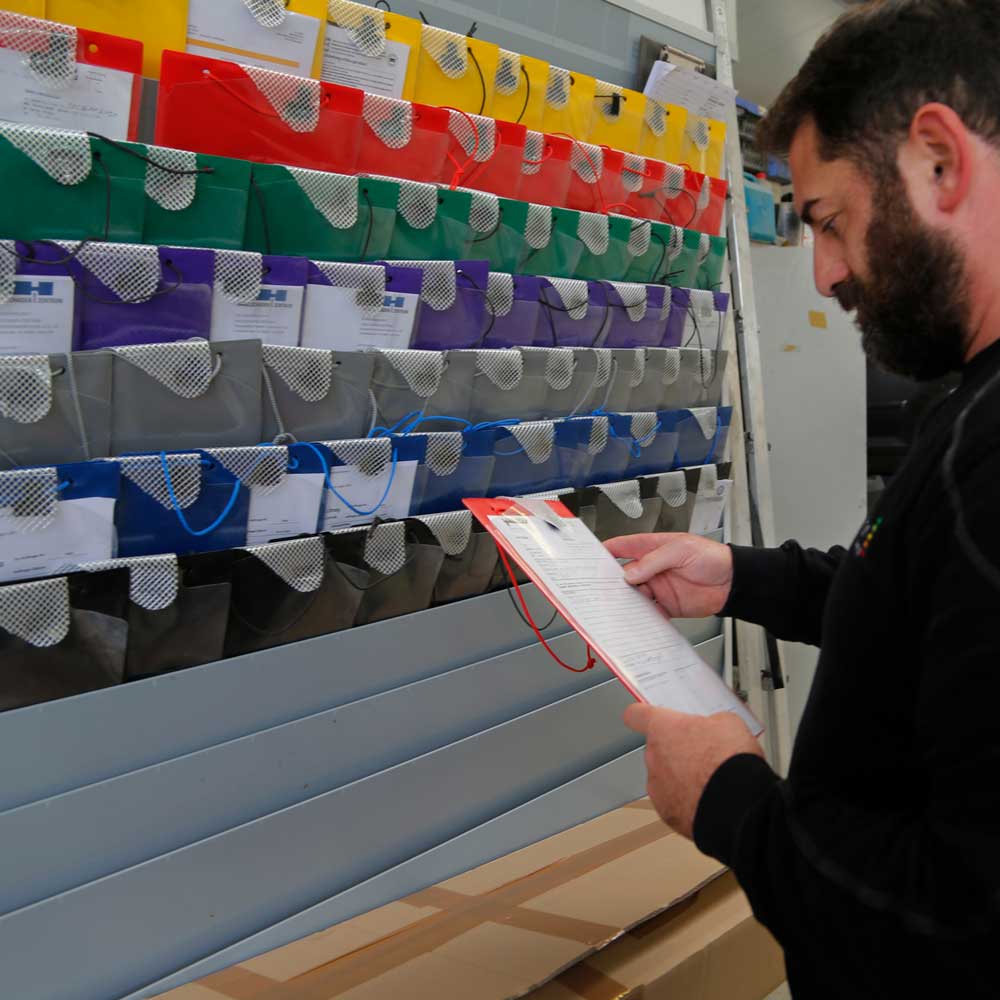 jakobson-services-versicherung-web Services-Versicherungsabwicklung-Der Abteilungsleiter schaut sich ein Dokument vor einem Regal mit der Dokumentenablage an