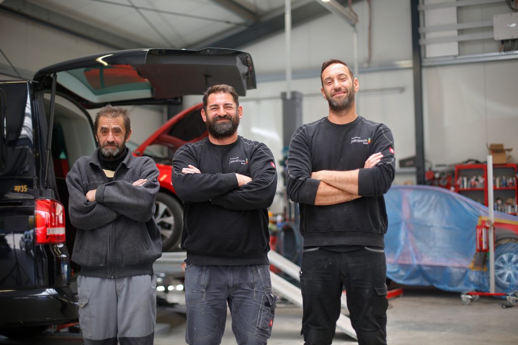 Über Uns-Das Team aus dem Abteilungsleiter in der Mitte sowie zwei Mitarbeitern links und rechts von ihm mit nach vorn verschränkten Armen